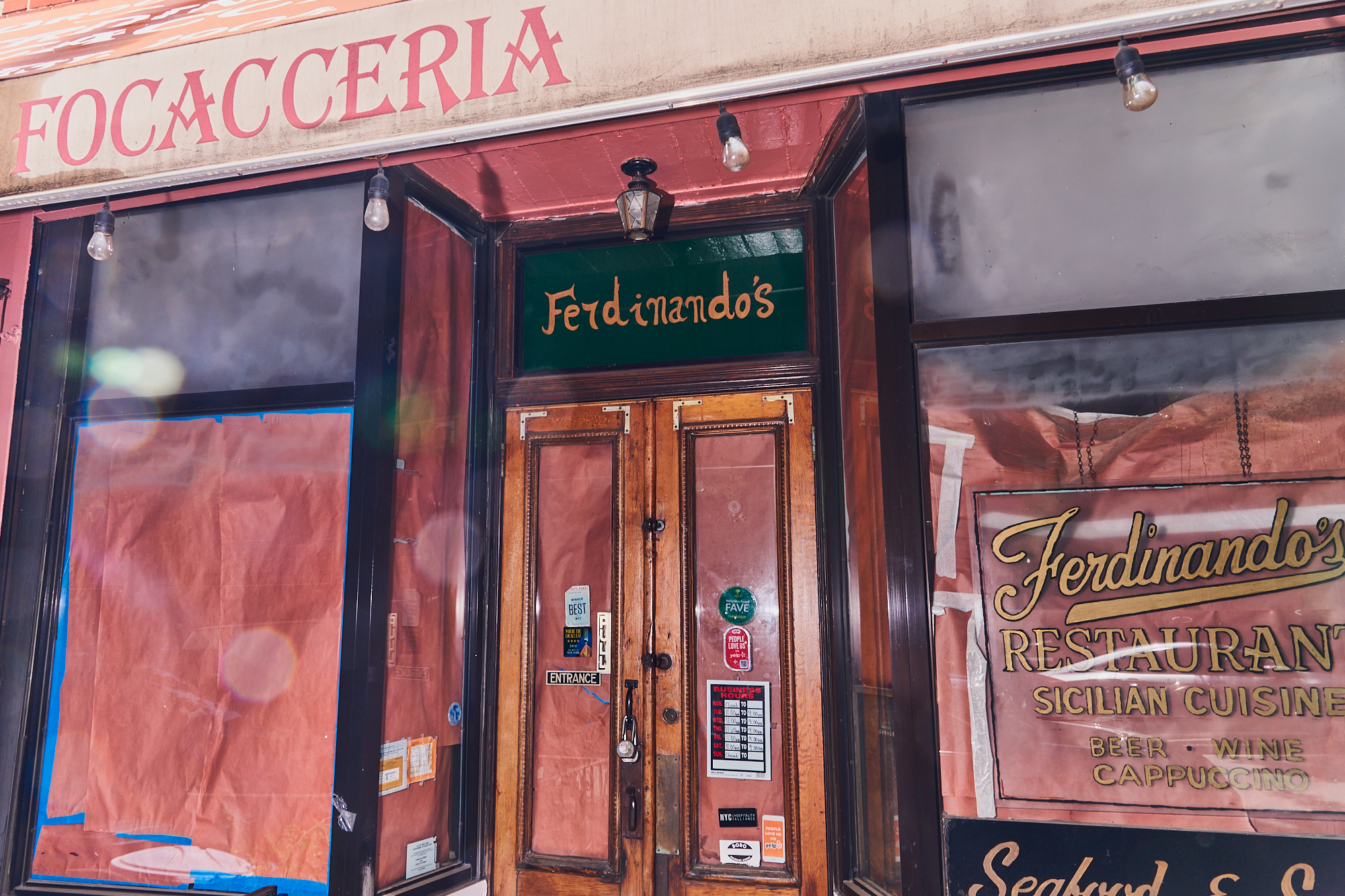 A restaurant with its windows covered in butcher paper and an awning reading FOCACCERIA.