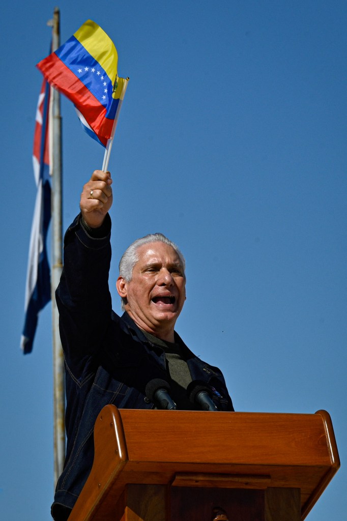 Cuba's President Miguel Diaz-Canel delivers a speech, fluttering a Venezuelan national flag.