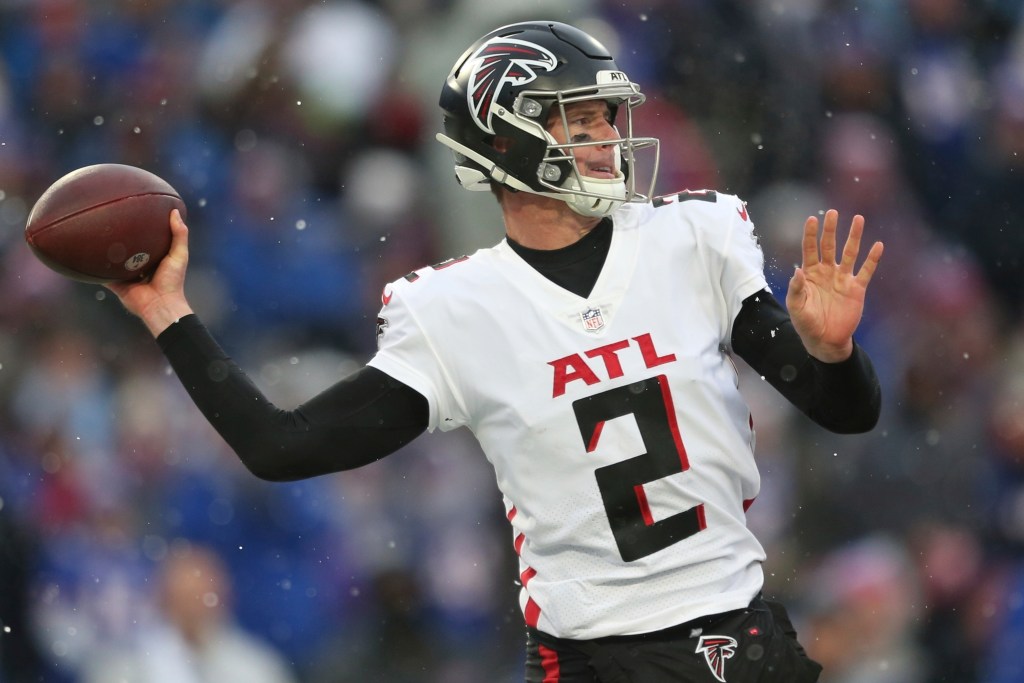 Falcons quarterback Matt Ryan wearing a white jersey with “ATL 2” and a black helmet, holding a football and preparing to throw.