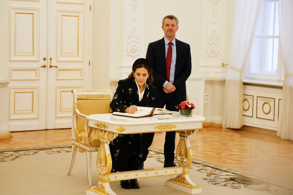 Queen Mary of Denmark signs the guest book of Lithuania's President as King Frederik X of Denmark looks on at the Presidential Palace in Vilnius on 28 January