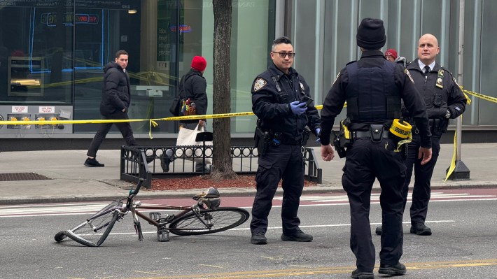 NYPD officers stand near a mangled bicycle that belonged to the victim