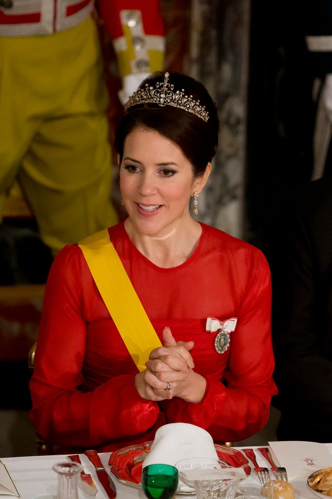 Mary in red dress and tiara at banquet table