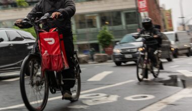 A delivery worker carries a DoorDash bag during a delivery in New York