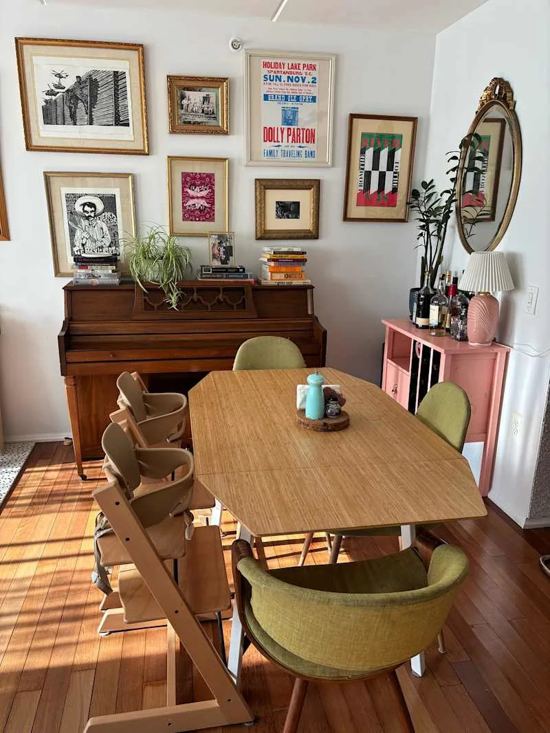 Dining area featuring a wooden table, green chairs, a piano, and framed artwork on the walls.