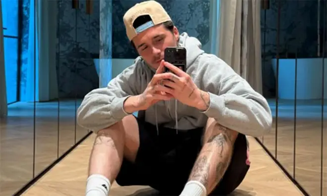 Brooklyn Beckham wearing a grey hoodie taking a selfie