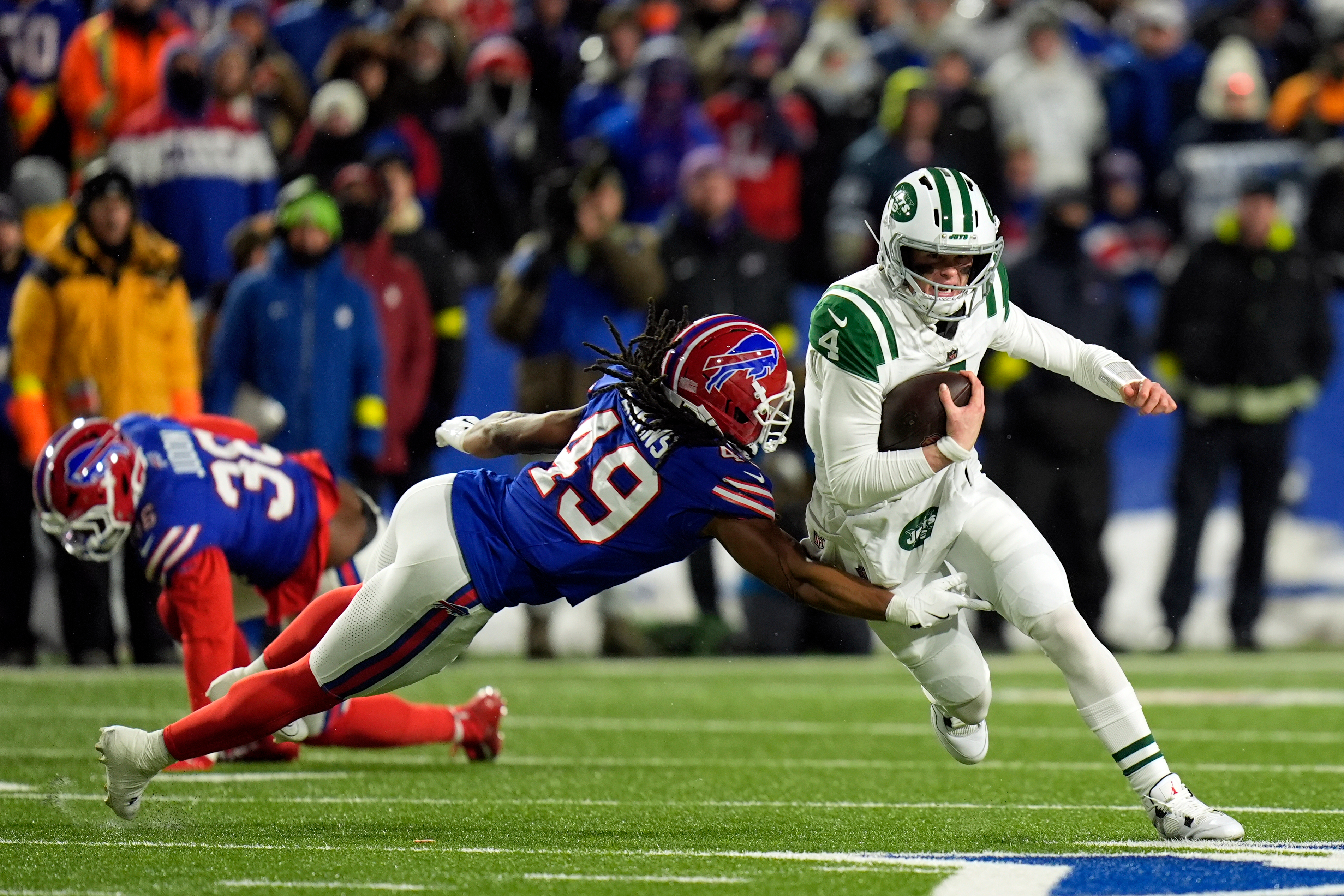 New York Jets quarterback Brady Cook (4) tries to scramble past Buffalo Bills linebacker Keonta Jenkins (49) in the first half of an NFL football game Sunday, Jan. 4, 2026, in Orchard Park, N.Y. (AP Photo/Seth Wenig)