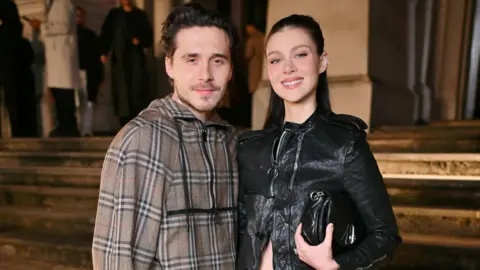 Getty Images Brooklyn and Nicola Peltz Beckham at Burberry's winter show in 2025, they are both wearing the classic Burberry check