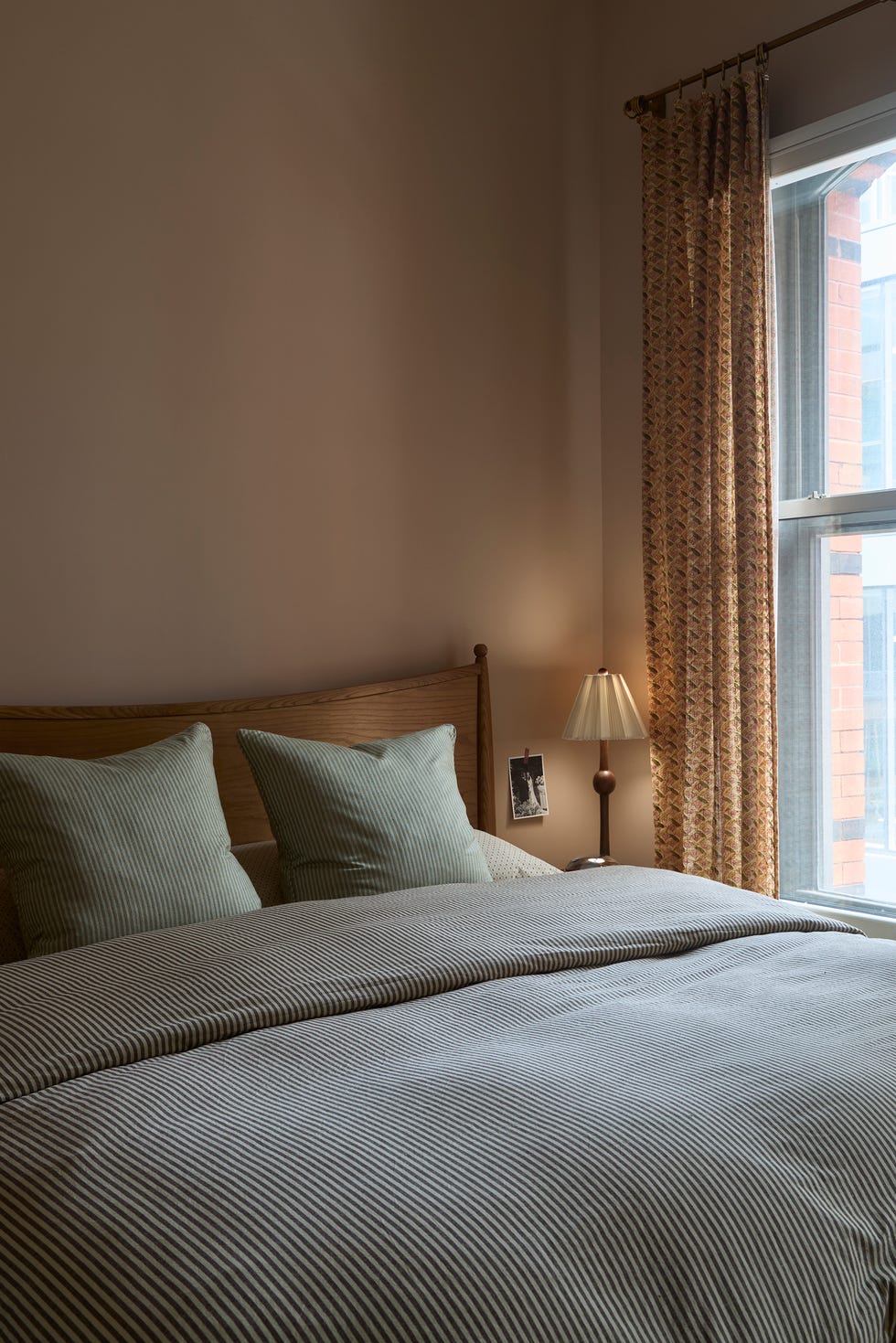 Cozy bedroom with a bed, pillows, lamp, and window.