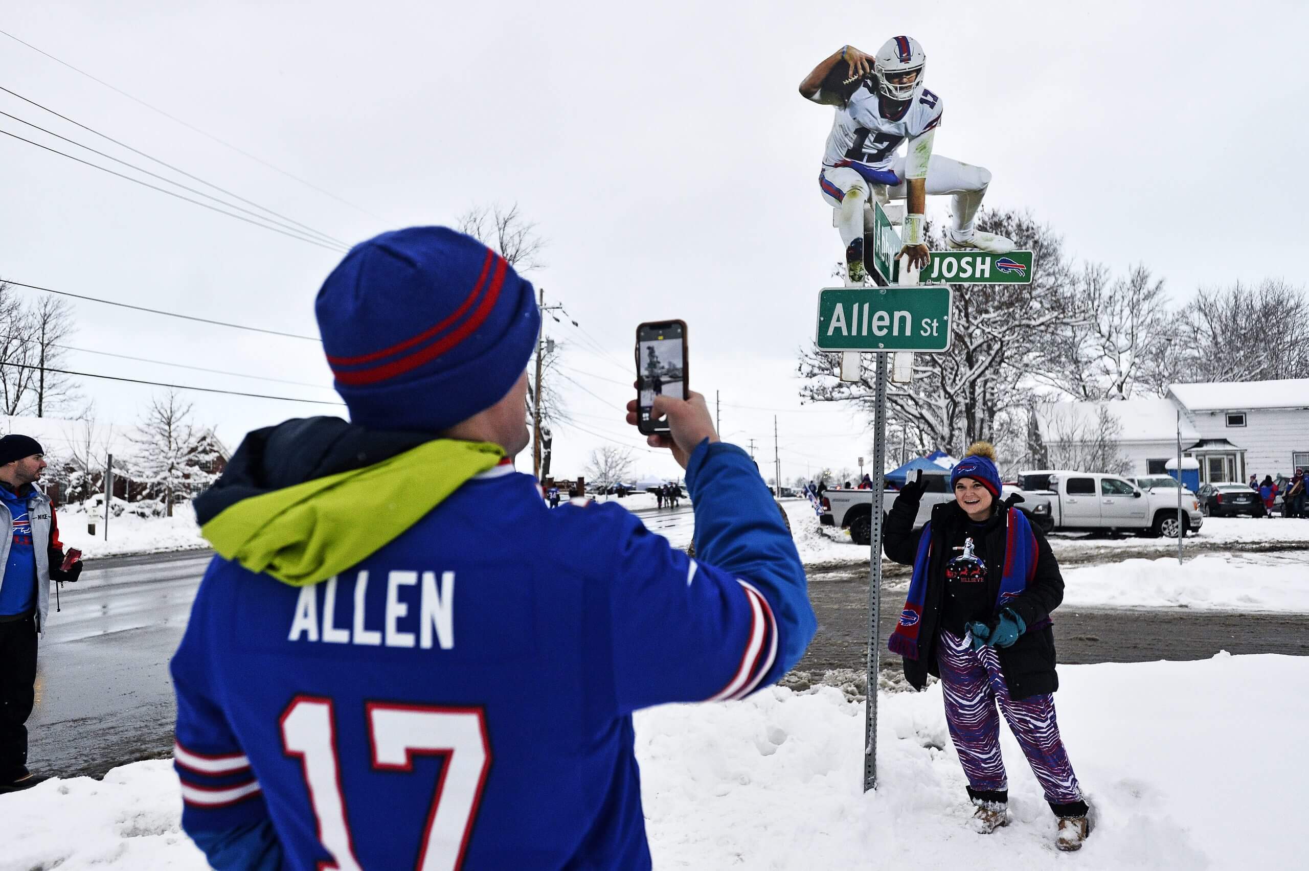 Buffalo Bills fans take a photo next to a street sign for Allen St. featuring a cutout of Bills quarterback Josh Allen hurdling it, before an NFL football game between the Buffalo Bills and the Miami Dolphins in Orchard Park, N.Y., Saturday, Dec. 17, 2022.