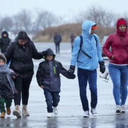 Immigrants walk in the rain towards the tents at a migrant housing location at Floyd Bennett Field, Tuesday, Jan. 9, 2024, in New York. AP Photo/Mary Altaffer, File