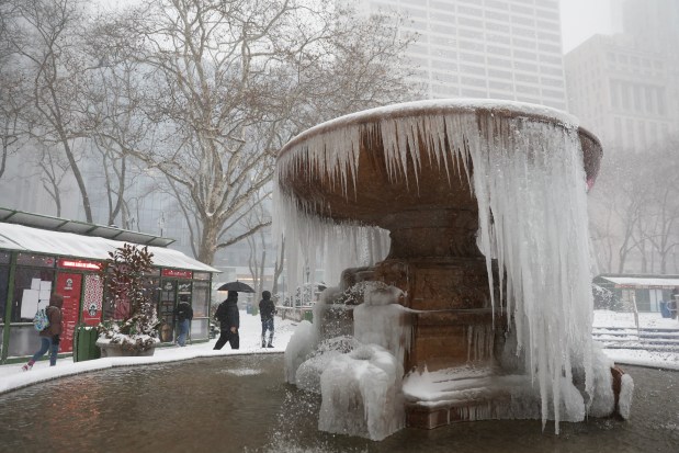 People walk around a frozen fountain at Bryant Park during a winter storm, Sunday, Jan. 25, 2026, in New York. (AP Photo/Heather Khalifa)