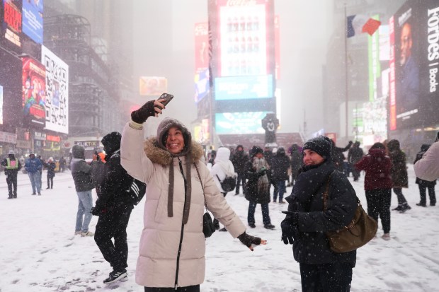 People take photos in Times Square during a winter storm, Sunday, Jan. 25, 2026, in New York. (AP Photo/Heather Khalifa)