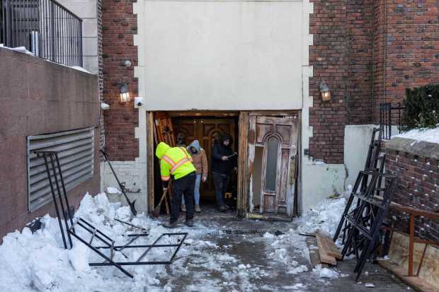 People clean up the scene where a car slammed into the entrance of the Chabad Lubavitch world headquarters, Thursday, Jan. 29, 2026, in New York. (AP Photo/Yuki Iwamura)