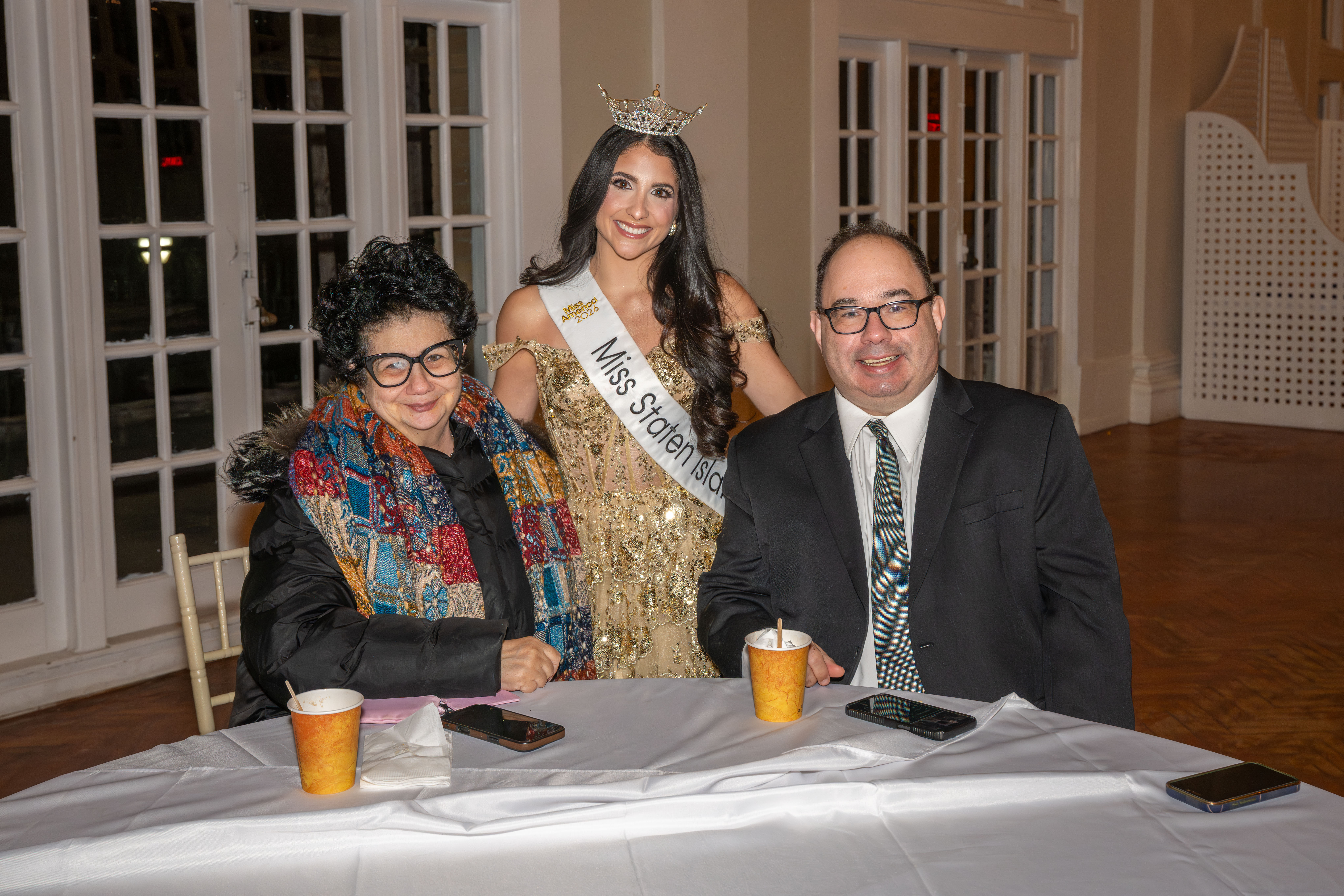 Lourdes Scholl, Gabriella Marinelli, Miss Staten Island 2026, and Michael Scholl pose for a photo during a fashion show at the Grand Colony Hall in Seaview on Saturday, January 24, 2026. The event, organized by the Albanian organization Zëri Ynë - Our Voice, aimed to raise money for the fight against pediatric cancer. (Owen Reiter for the Advance/SILive.com)