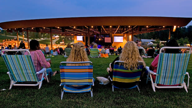 Four people sit in chairs watching a concert at Bethel Woods from the lawn
