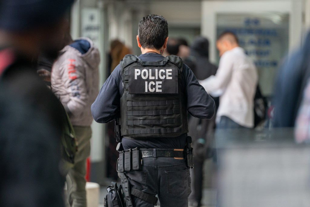 An ICE police officer with "POLICE ICE" written on the back of his uniform.