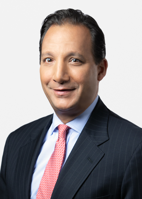 Portrait of a man in a pinstripe suit and patterned red tie.