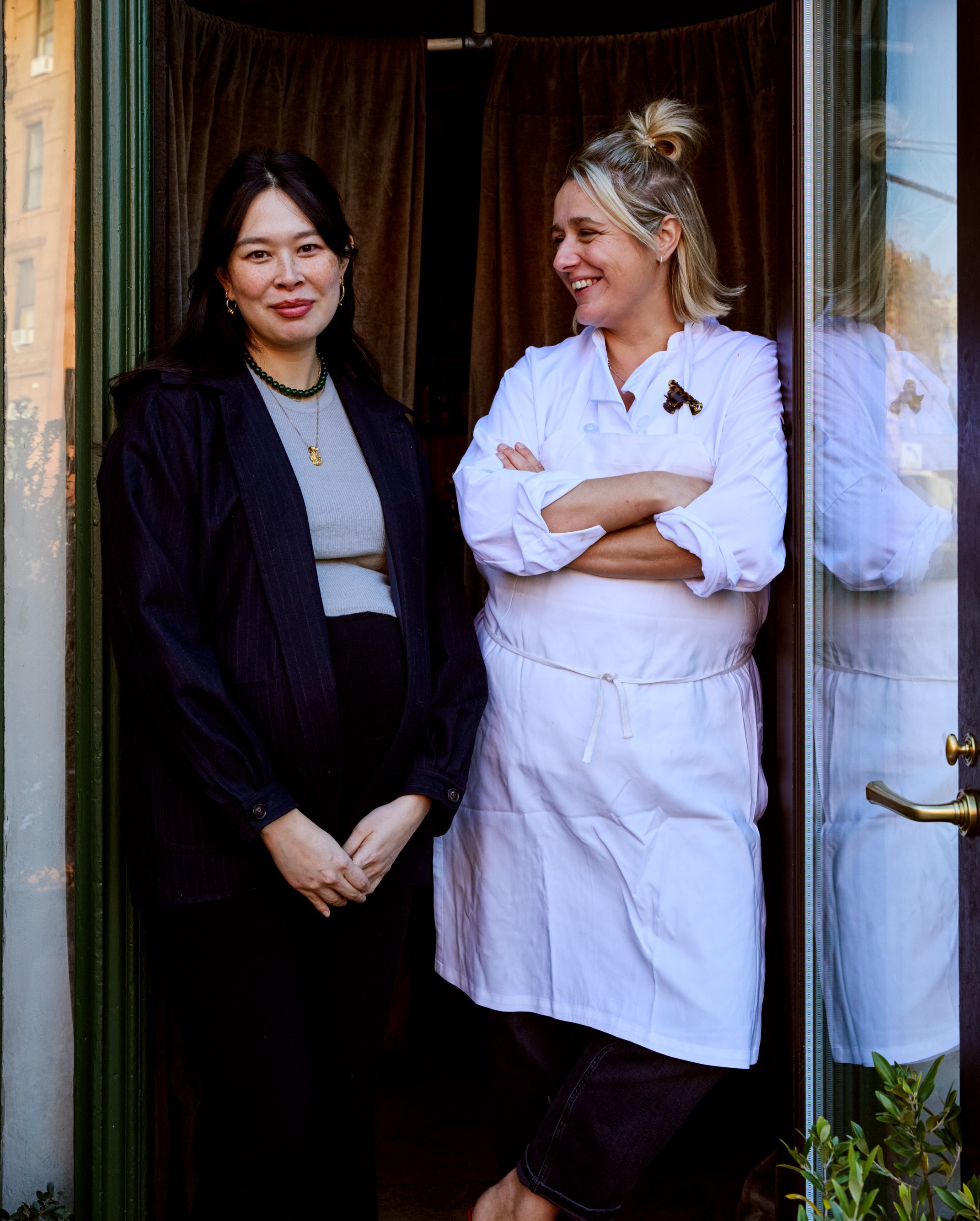 Two people standing at a restaurant door.