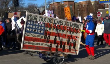 person walking with anti-war sign on cart during march