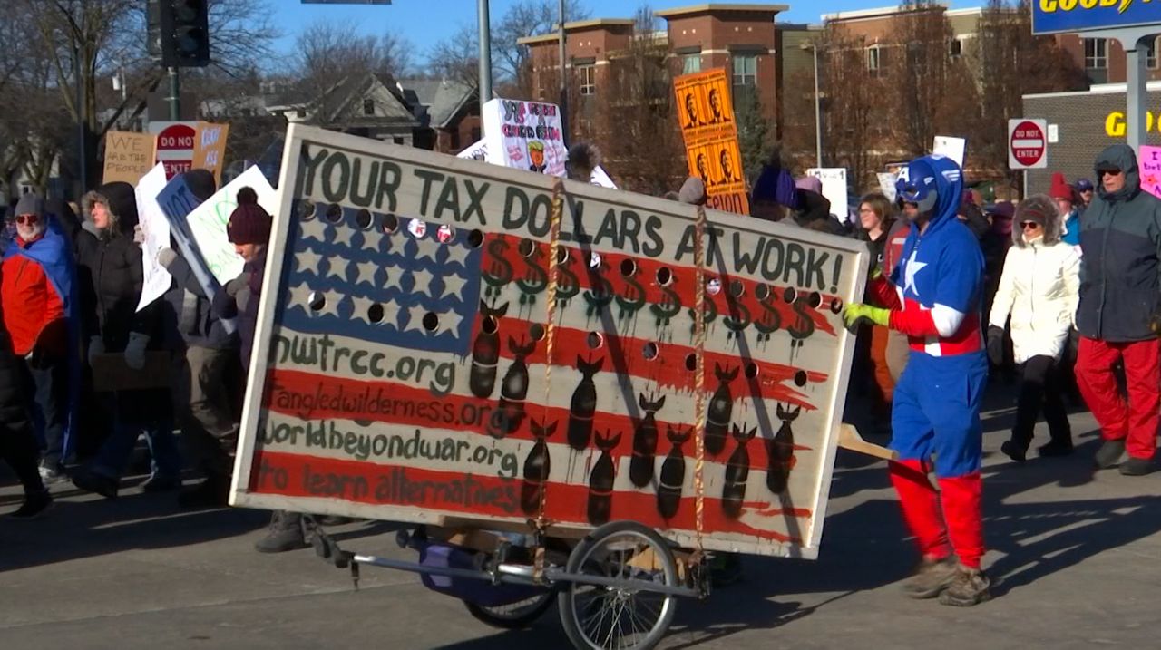 person walking with anti-war sign on cart during march