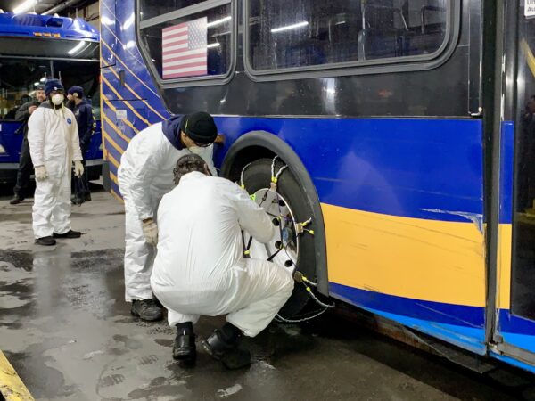 An MTA team fit snow chains onto the rear tires of transit buses on Friday. Photo: Mary Frost, Brooklyn Eagle