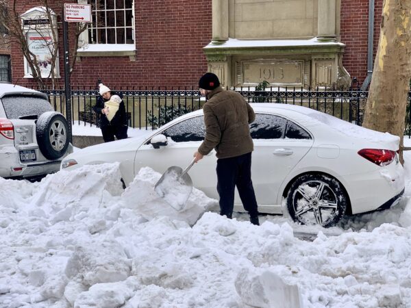 A man digs his car out of the snow on Orange Street, as his wife and baby wait nearby. Photo: Mary Frost, Brooklyn Eagle