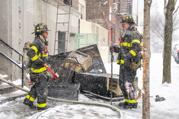 Firefighters work in the snow at a Bronx apartment fire on Sunday.