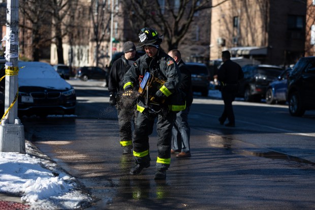 A firefighter puts down salt where blood was washed away after a man on a bicycle was fatally hit by a truck on the corner of Sanford Ave. and 160th St. in Queens on Tuesday, Jan. 20, 2026. (Shawn Inglima/ New York Daily News)