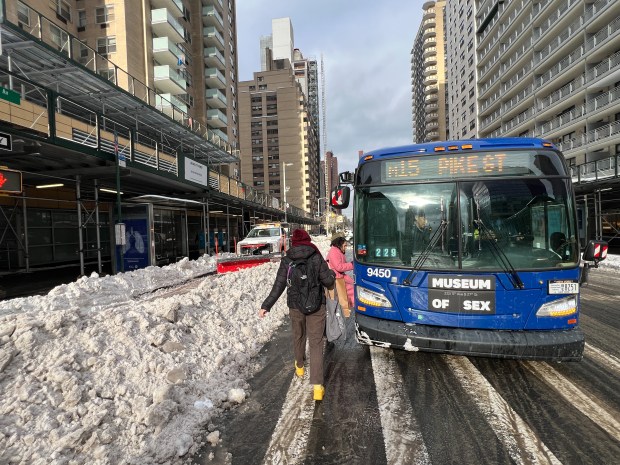 Riders board an M15 as a Department of Sanitation worker plows out a bus stand on the corer of E. 86th St. and 2nd Ave. Monday, January 26, 2026, in Manhattan, New York. (Barry Williams/ New York Daily News)