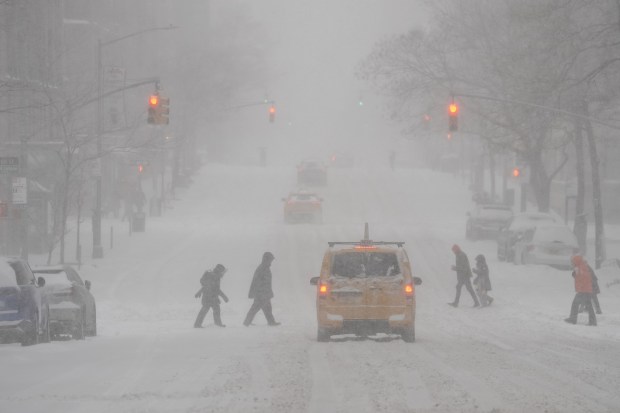 Pedestrians cross Madison Ave. in the snowstorm on Sunday. 