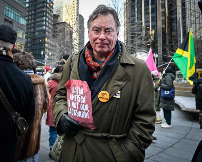 man wearing a trench coat holding protest flyer