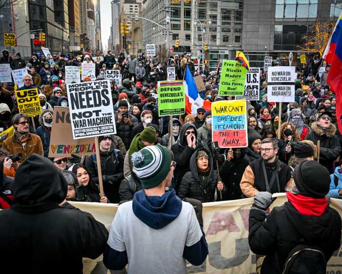 Large group gathered in NYC street holding protest signs