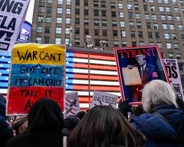large group of protestors holding signs outside in front of a building
