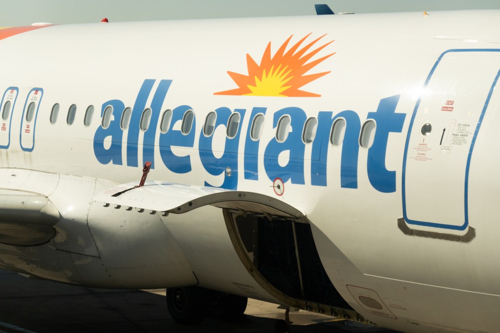 An Allegiant Airlines plane at a gate at Orlando International Airport with the cargo hold open.