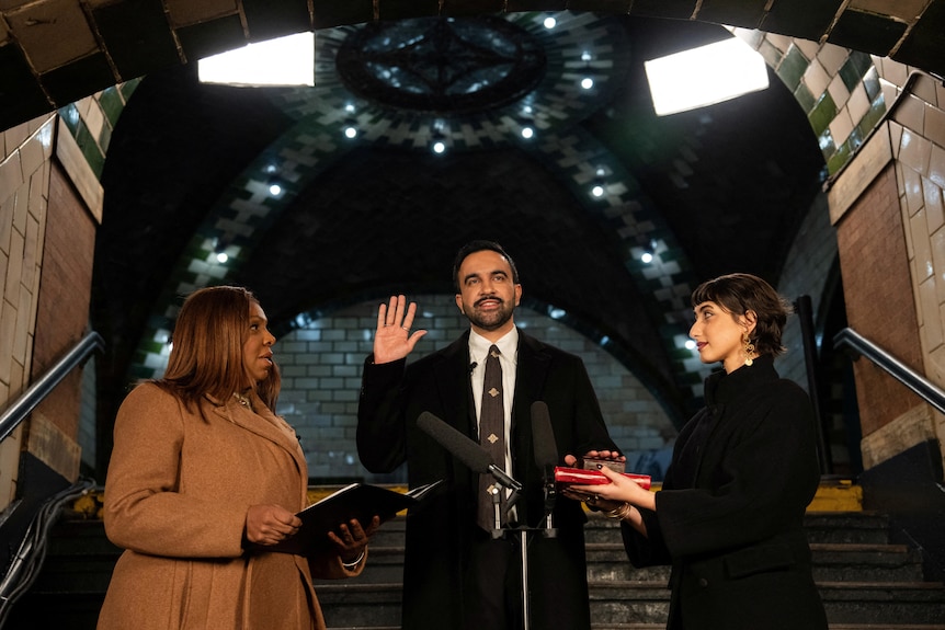 Zohran Mamdani raises his right hand as he takes an oath