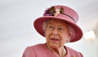 Queen Elizabeth wearing a pink hat and coat looking to the side