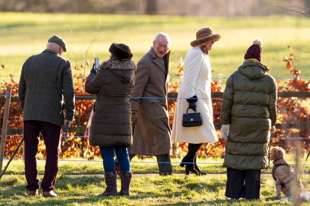 King Charles III and Queen Camilla walking to church with members of public looking on