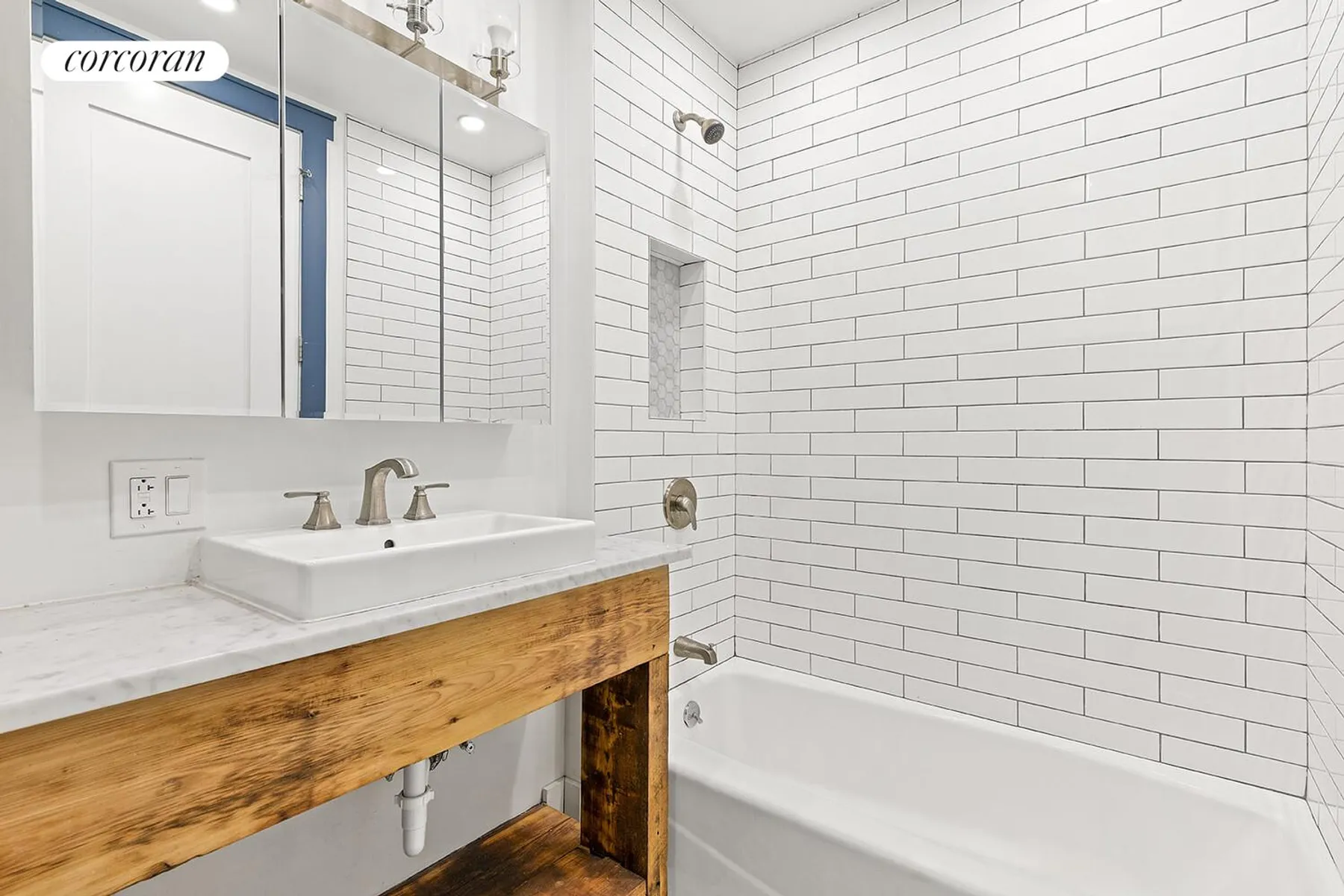 bathroom with wood vanity, white fixtures, subway tile