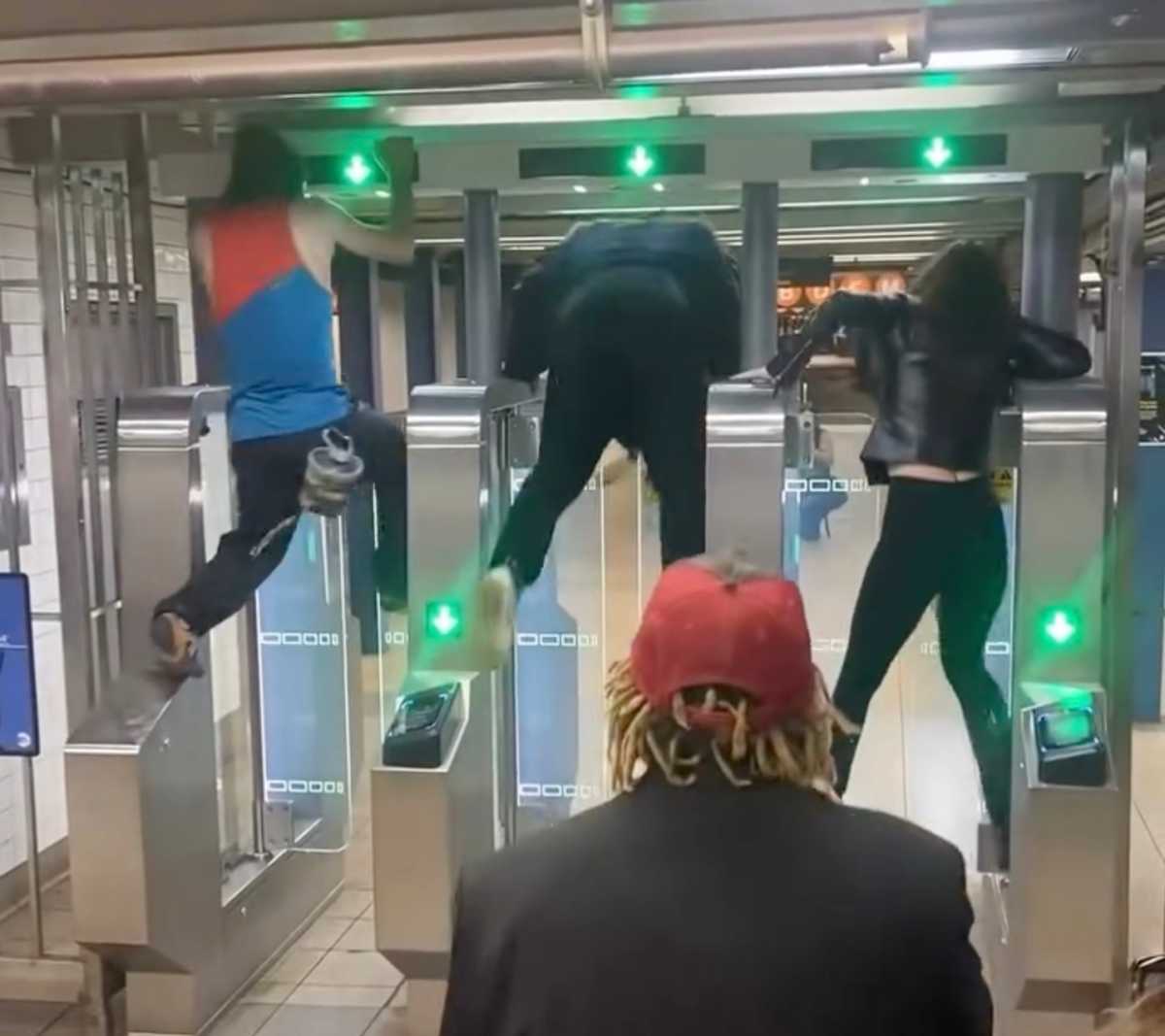 People hopping over modern turnstiles in "Fare Evasion Olympics" at Manhattan station