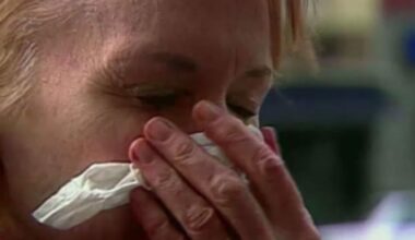 woman holds tissue to face to either blow nose or sneeze