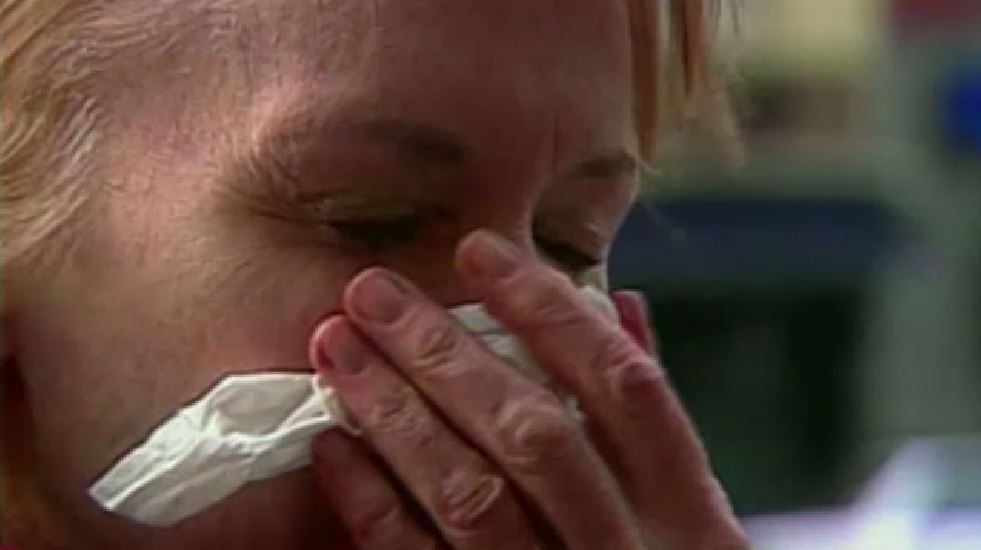 woman holds tissue to face to either blow nose or sneeze