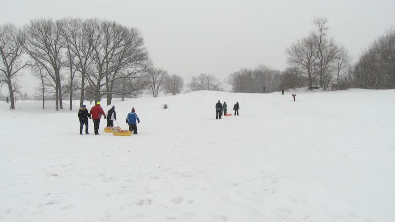 people walking up frear park hill in the snow, carrying sleds