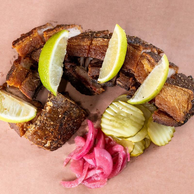 Some meat with lime wedges and pickled onions on butcher paper.