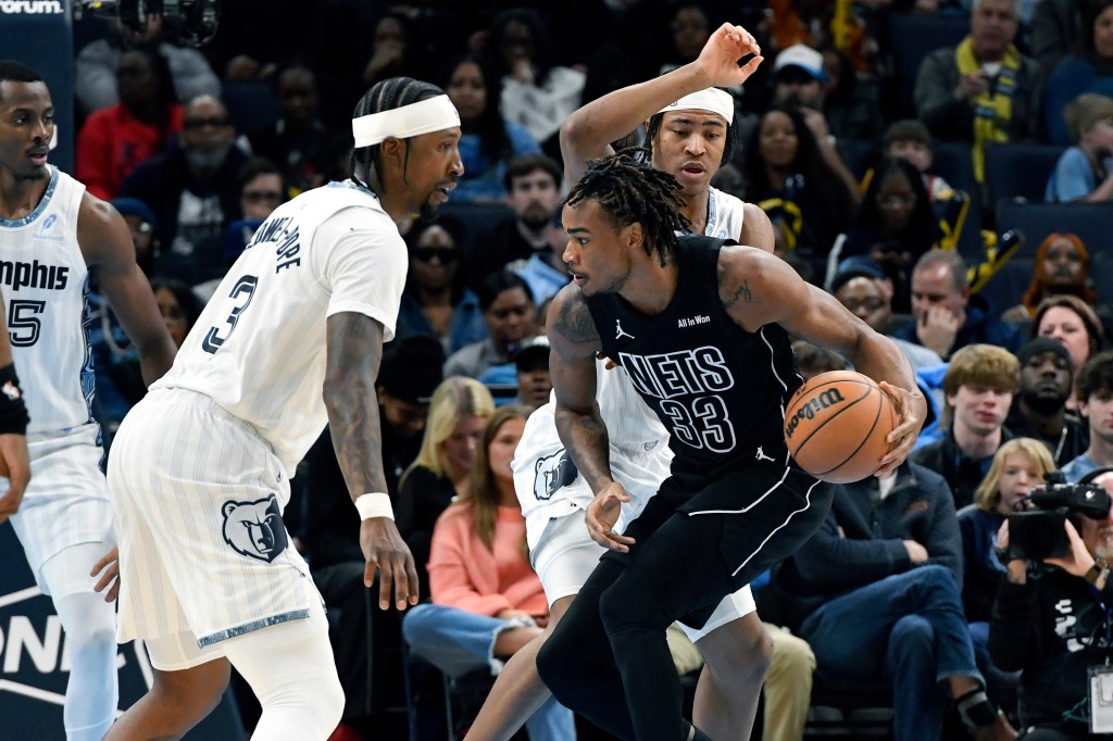 Brooklyn Nets center Nic Claxton (33) handles the ball against Memphis Grizzlies guard Kentavious Caldwell-Pope (3) and forward Jaylen Wells, top right, in the first half of an NBA basketball game Sunday, Jan. 11, 2026, in Memphis, Tenn. 