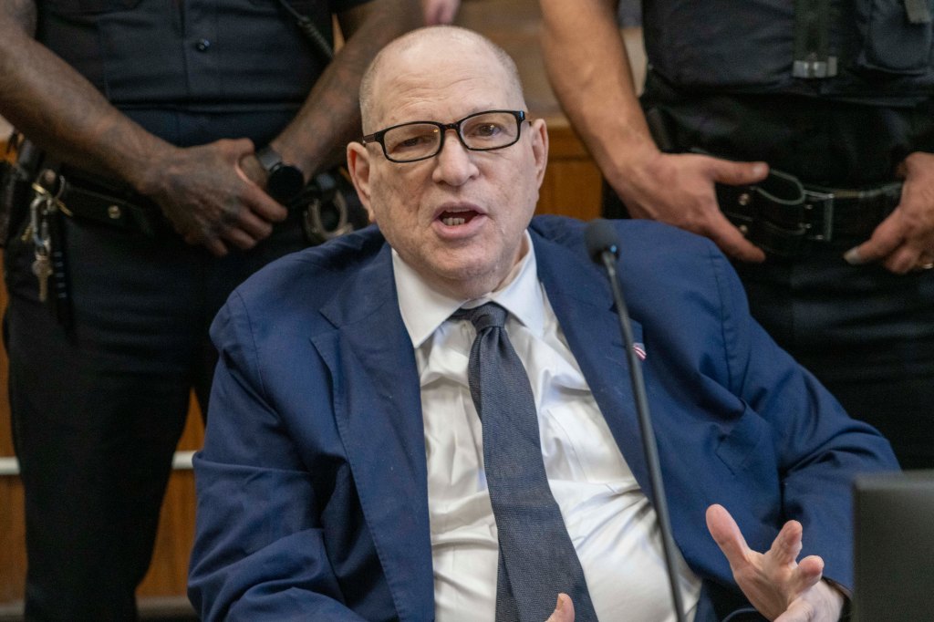 Harvey Weinstein speaking in court while surrounded by officers.