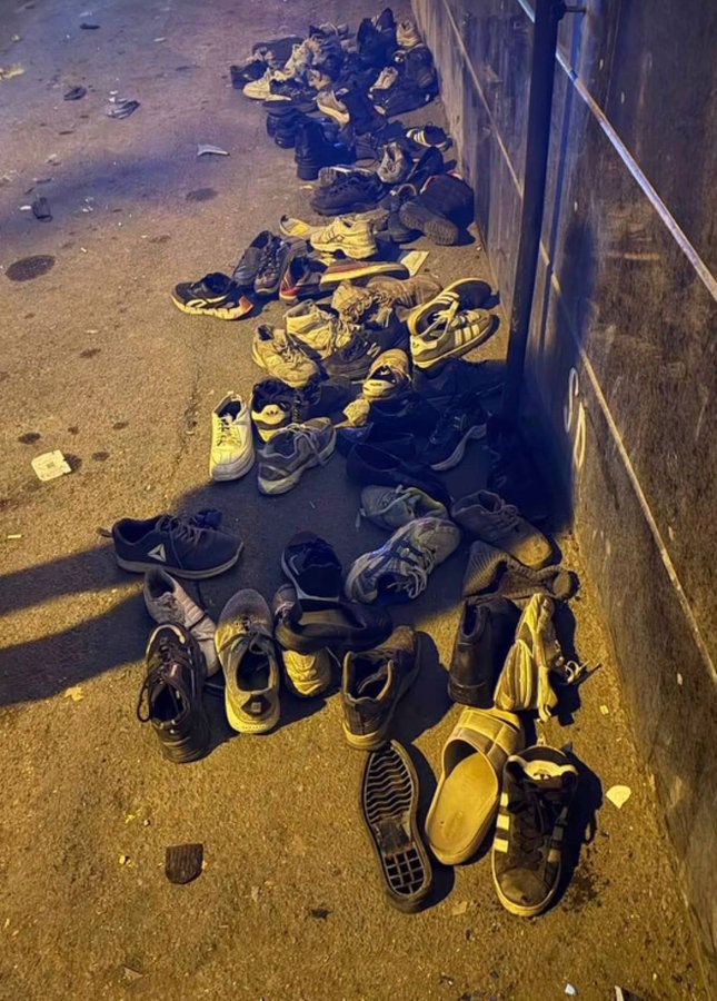 A pile of abandoned shoes on the ground, illuminated by a harsh light.