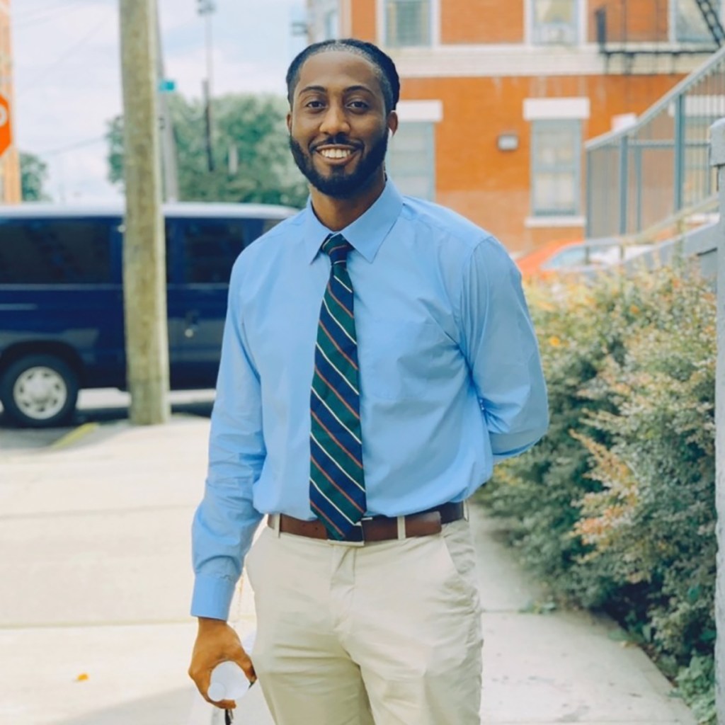Jayvone Johnson in a light blue shirt, striped tie, and khaki pants.