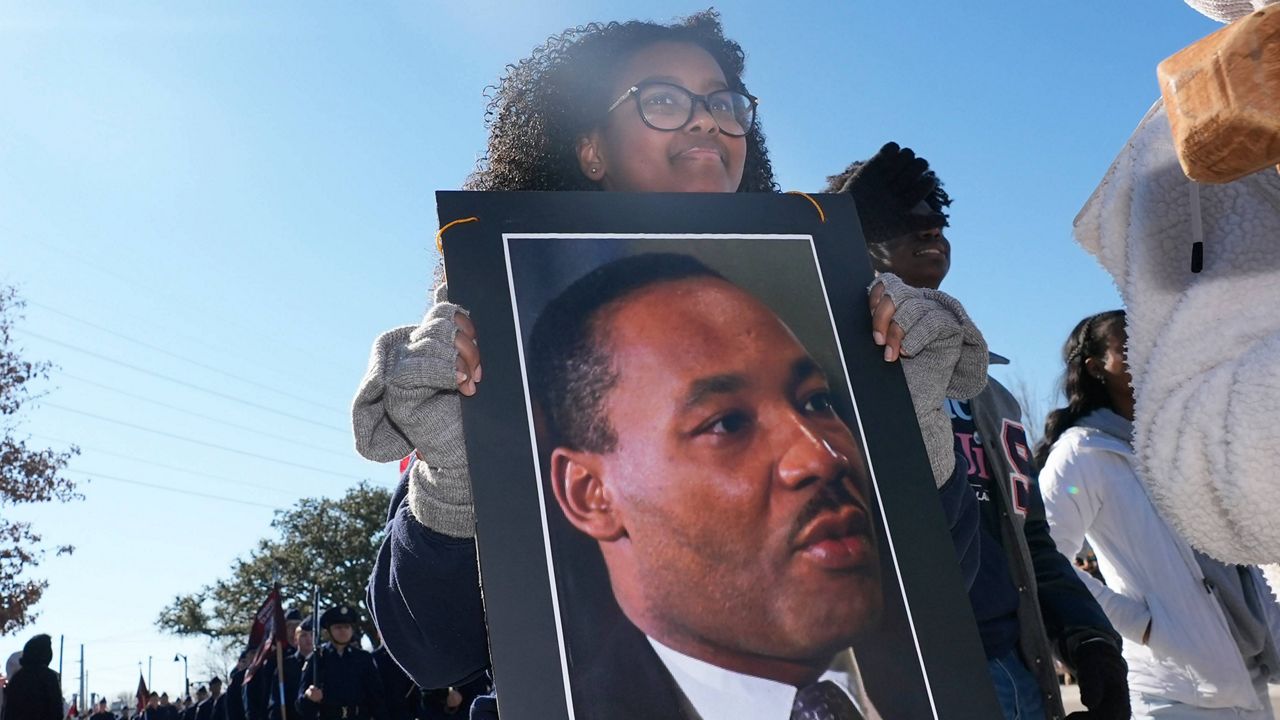 teenager walks in parade holding martin luther king jr photo