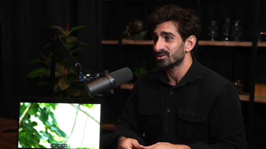 Paul Rosolie talking about uncontacted tribes with a laptop displaying footage of nature.