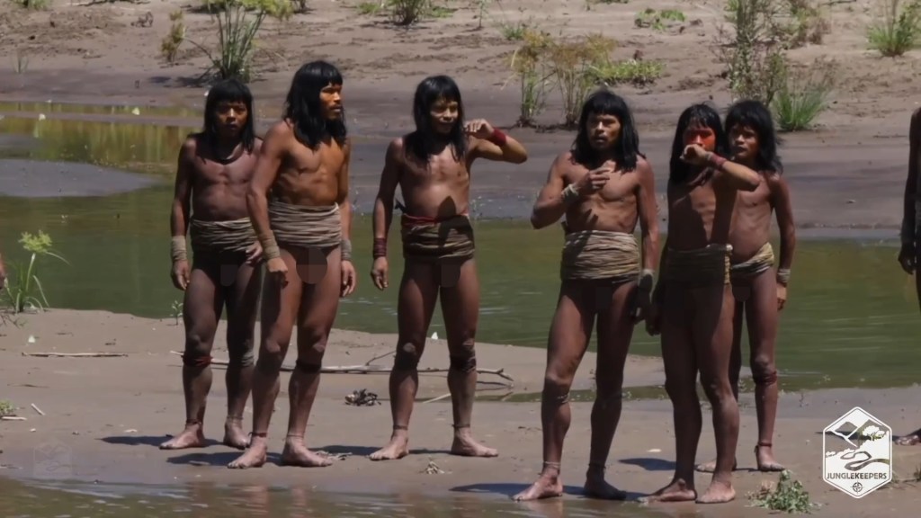 Six members of an uncontacted Amazonian tribe stand by a river.